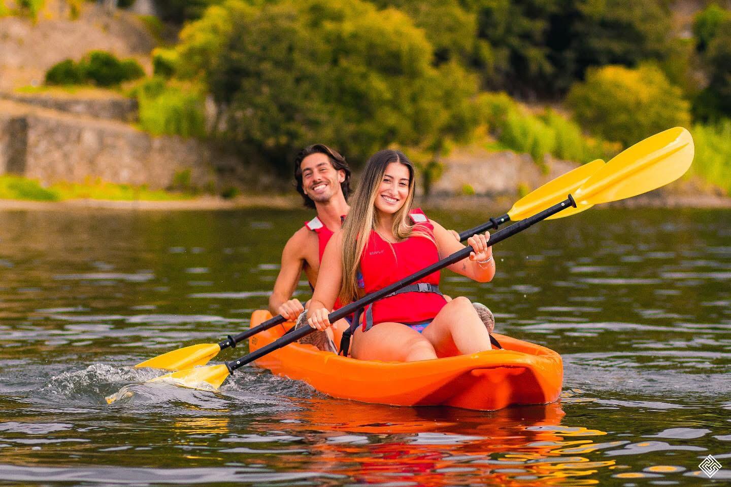 A smiling couple paddling a double kayak on the river